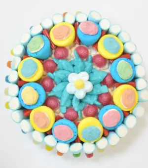 Tarta de chuches redonda con fresones rellenos y esponjitas en forma de flor, ideal para compañeros de trabajo.