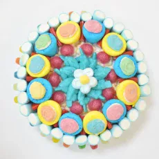 Tarta de chuches redonda con fresones rellenos y esponjitas en forma de flor, ideal para compañeros de trabajo.