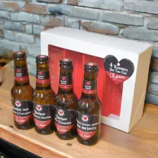 Estuche con 4 cervezas Estrella Galicia y mensajes románticos, regalo para pareja En una encimera con pared detrás.