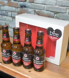 Estuche con 4 cervezas Estrella Galicia y mensajes románticos, regalo para pareja En una encimera con pared detrás.