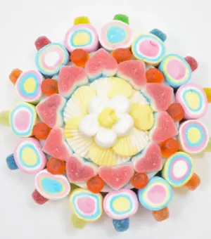 Tarta con golosinas y esponjitas redonda de 250 gramos vista desde un ángulo lateral, mostrando el detalle de las esponjitas alrededor.