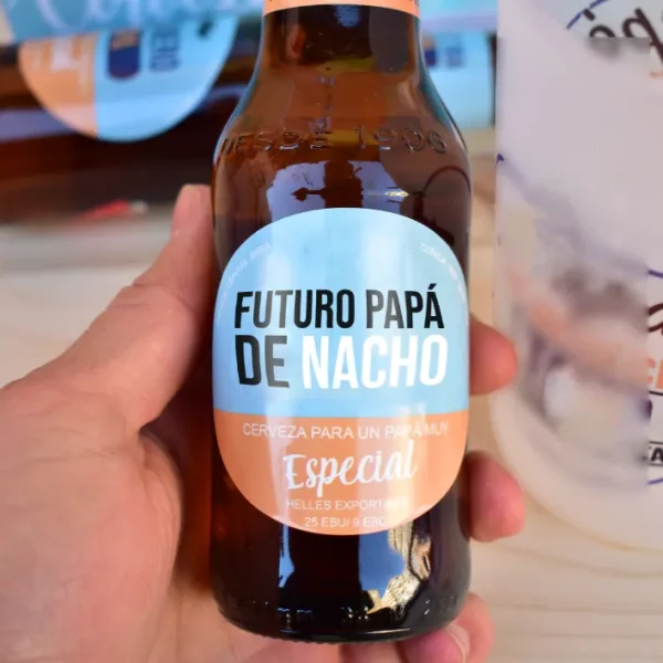 Botellín de cerveza agarrado con la mano. "Futuro papá de Nacho"