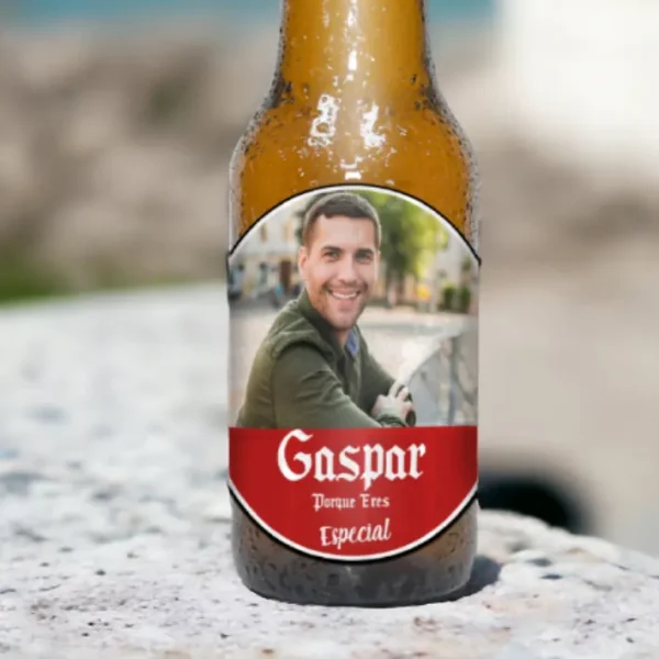 Botellín de cerveza personalizado visto desde cerca, con nombre "Gaspar" y foto, en una ubicación al aire libre junto al mar.