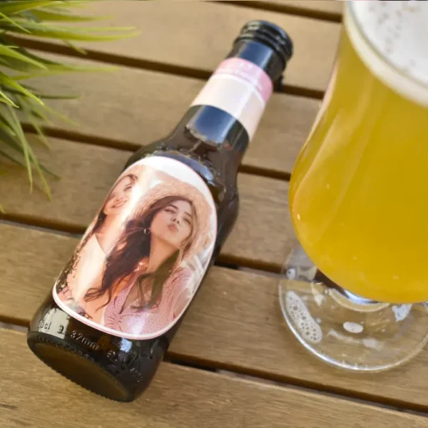 Botellín de cerveza personalizado junto a un vaso de cerveza lleno, resaltando la personalización del diseño.