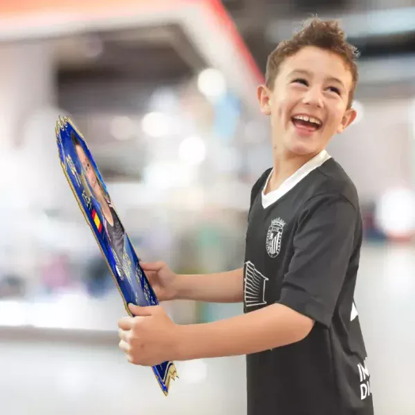 Niño sonriendo mientras sostiene una Carta del FIFA personalizada con su propia imagen.