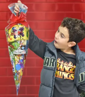 Cucurucho de chuches sin glute. agarrado por un niño modelo. Se ve el tamaño del cucurucho. e chuches.