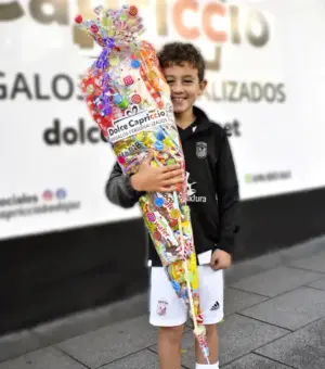 Cucurucho de chuches gigante sujetado por un niño feliz.