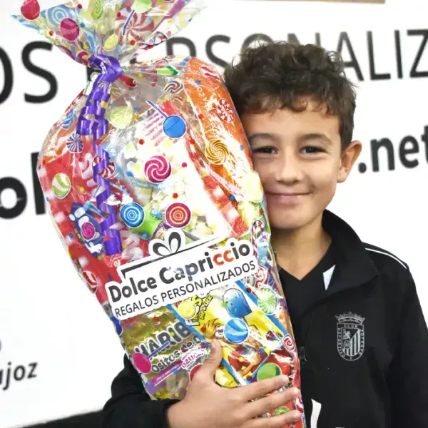 Cucurucho de chuches gigante sujetado por un niño feliz.