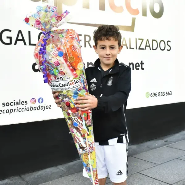 Cucurucho de chuches gigante sujetado por un niño feliz.