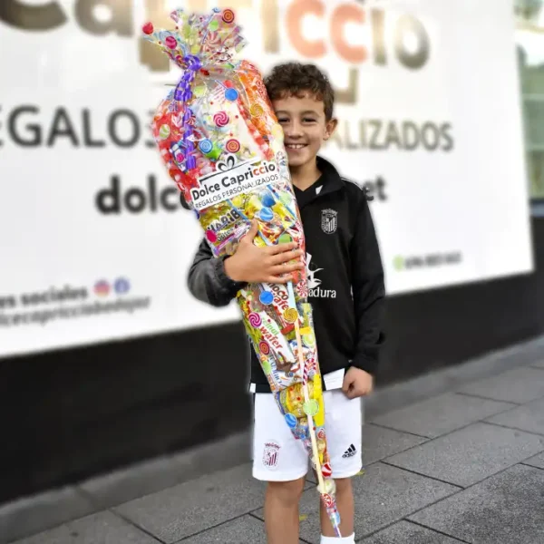 Cucurucho de chuches gigante sujetado por un niño feliz.