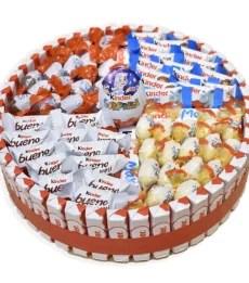 Primer plano de los chocolates Kinder Bueno Mini y Kinder Sorpresa sobre la tarta Kinder decorativa.