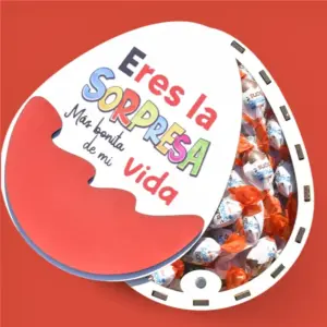 Caja de madera en forma de huevo kinder con la tapa abierta, se ve el relleno, que son SchokoBons.