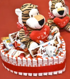 Tarta kinder en forma de corazón con un peluche arriba con un corazón que pone te quiero.
