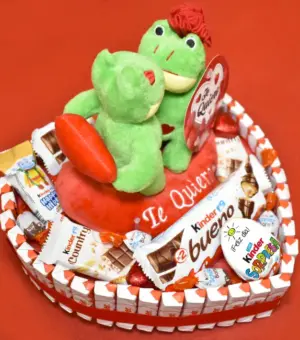 Tarta en forma de corazón repleta de kinder, con peluches de ranas besandose.