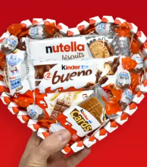 Tarta kinder en forma de corazón sujetada por una mano.