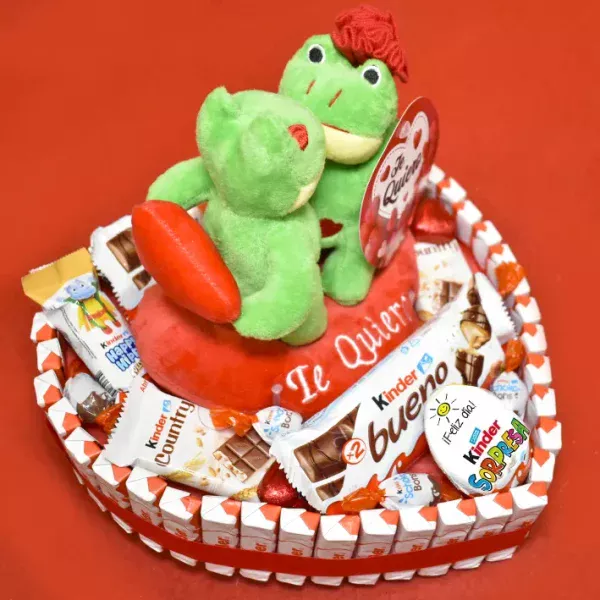 Tarta en forma de corazón repleta de kinder, con peluches de ranas besandose.