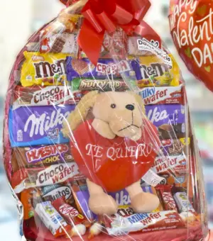 Cesta de chocolate para XL con un peluche con la palabra Te Quiero.El peluche tiene forma de perro. La cesta está envuelta con un papel celofán y lazo rojo.