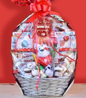 Cesta con chocolates surtidos y un peluche, ideal para regalar en San Valentín. Cerrada y envasada con un lazo rojo.