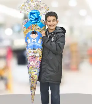 Cono XL agarrado por un niño. Se aprecia el tamaño enorme. El cono va personalizado con un vinilo de Mi Primera Comunión.