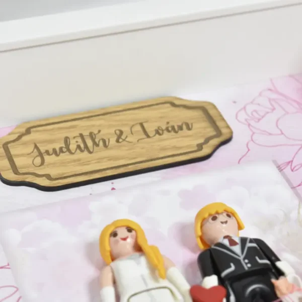Playmobil de un marco personalizado visto de cerca con sus nombres impresos en madera