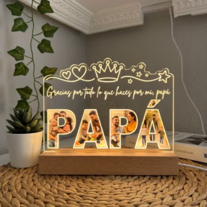 Lámpara de metacrilato con la palabra PAPÁ personalizada con fotos familiares y luz cálida LED sobre mesa de mimbre